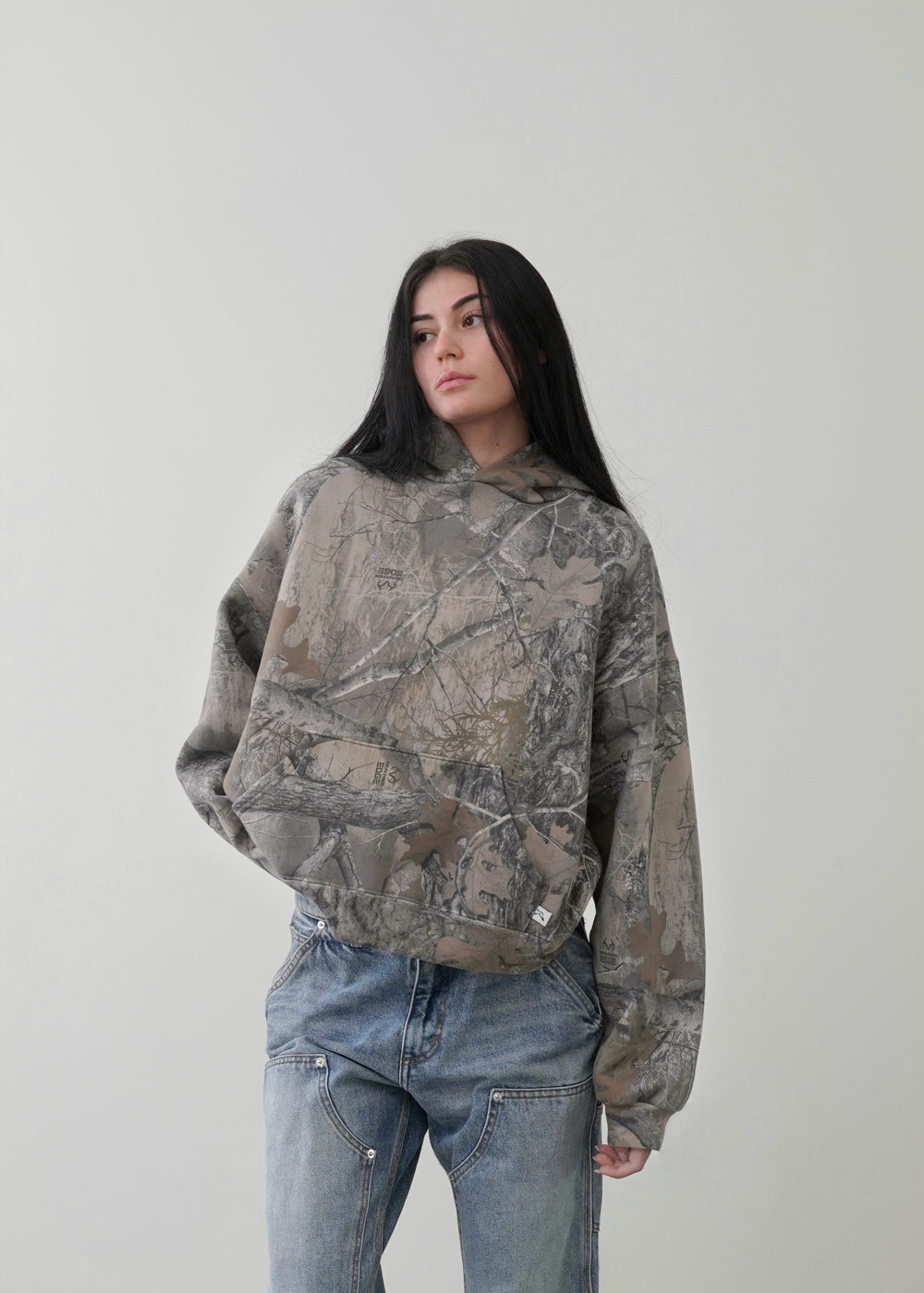 Close-up of female model wearing the Akimbo Camo Hoodie by Obscure Collective, highlighting the bold camo print. A stylish streetwear piece for modern fashion.