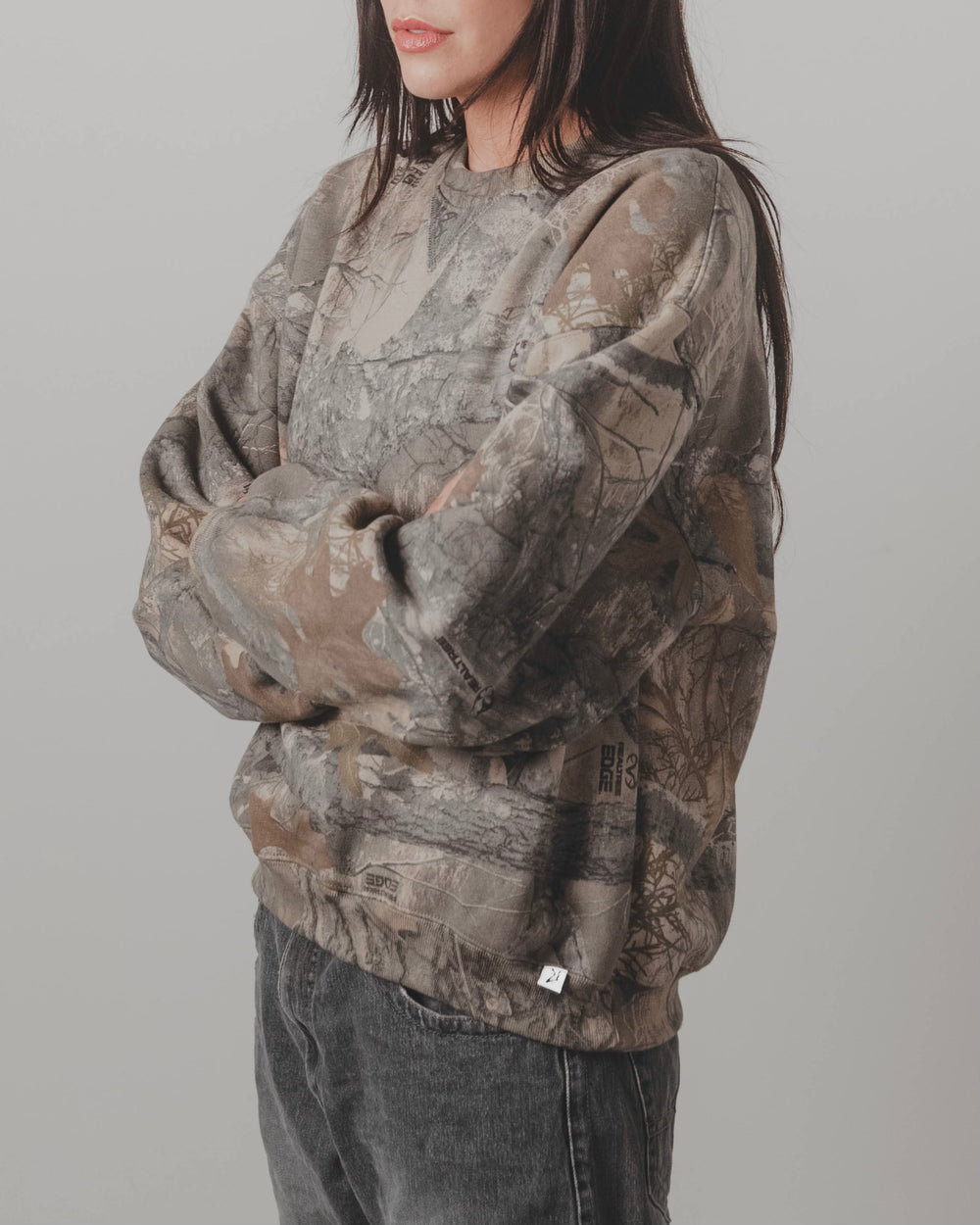 Model wearing the Akimbo Camo Sweater by Obscure Collective in side view, showcasing the camo pattern. The sweater embodies streetwear style and comfort.