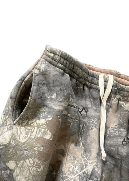 Front-facing closeup image of pocket and hip of the Akimbo Style Camo Sweatpants from Obscure Collective, featuring a distressed camouflage design, loose fit, and streetwear style, set against a white background.