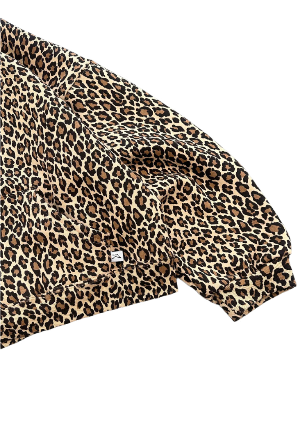 A close-up of the sleeve of a minimalist akimbo style leopard print hoodie, featuring subtle detailing and clean lines, set against a stark white background. The design reflects the understated aesthetic of obscure collective and streetwear culture, blending simplicity with modern urban style.